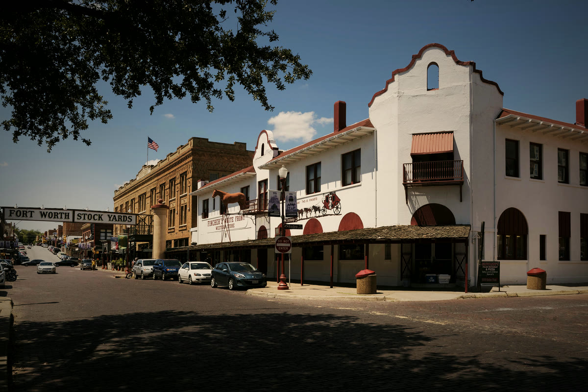 Storefronts on Exchange Avenue in the Fort Worth Stockyards in late-afternoon light, with the Fort Worth Stock Yards sign over the street